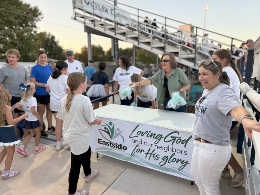 Church members handing out cotton candy to kids from an Eastside table at the football game